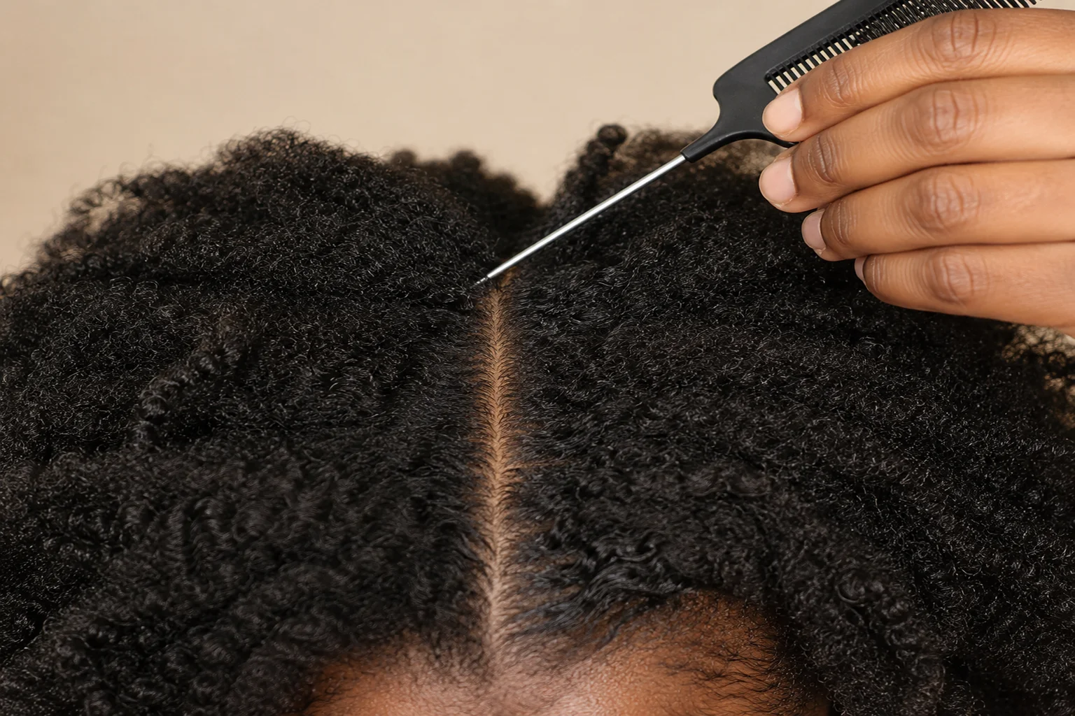 Rat tail comb creating a clean center part in 4C natural hair before Fulani braiding