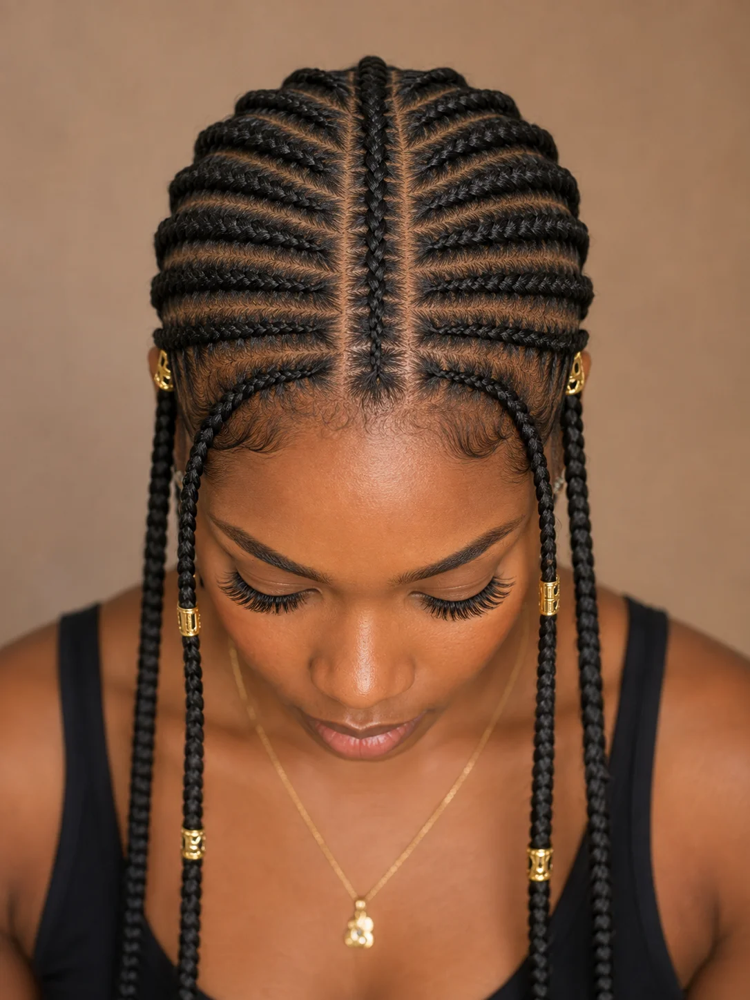Top-down view of Fulani braids showing the single center cornrow with symmetrical face-framing braids and gold cuffs